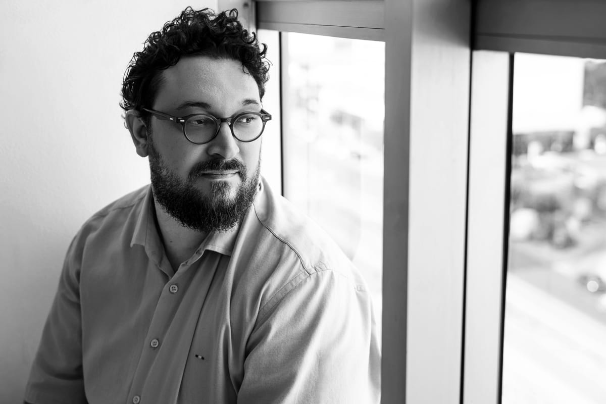 José Rizzotto Neto, psicólogo, junto à janela do consultório, em retrato preto e branco